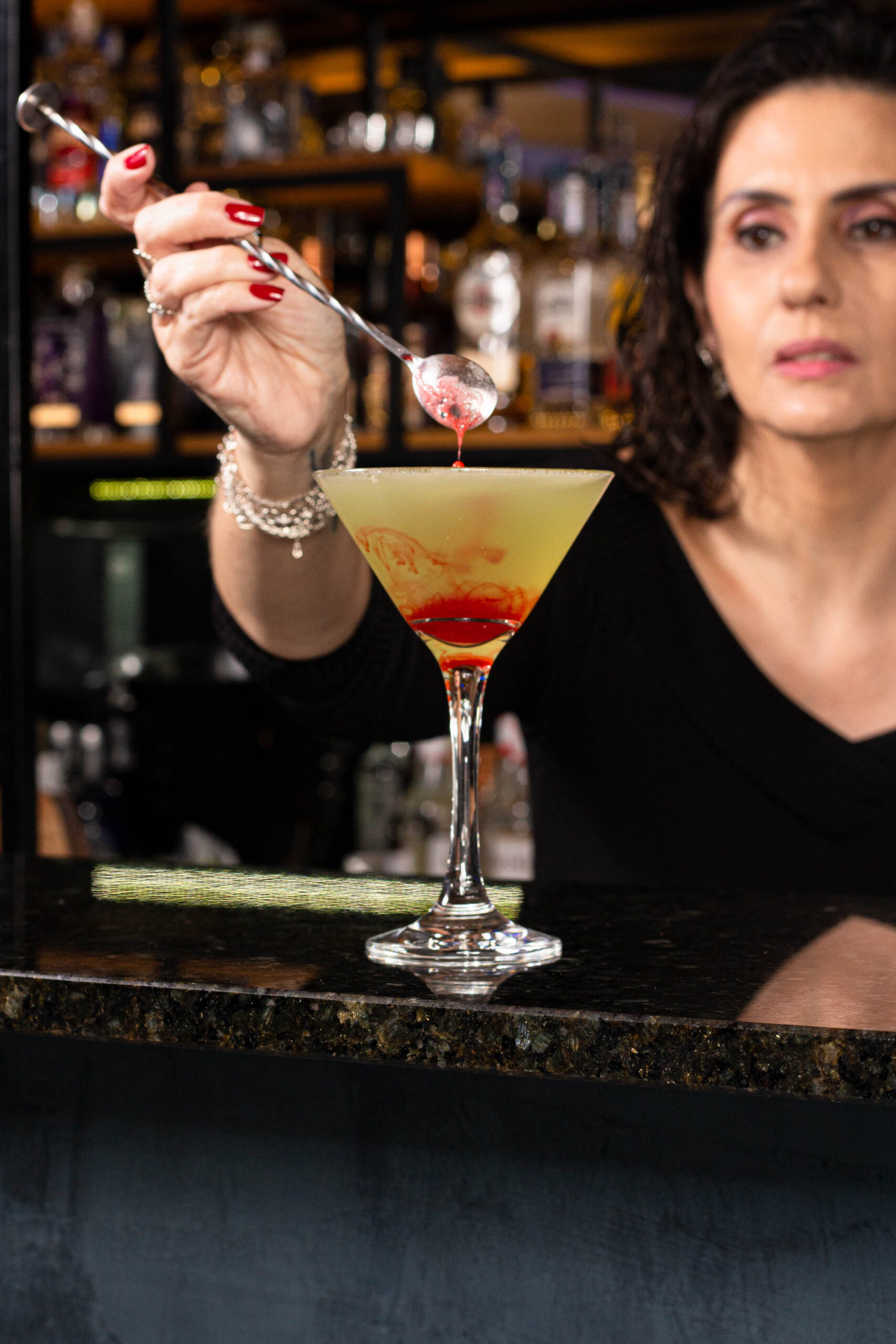 mulher misturando um drink com uma colher.