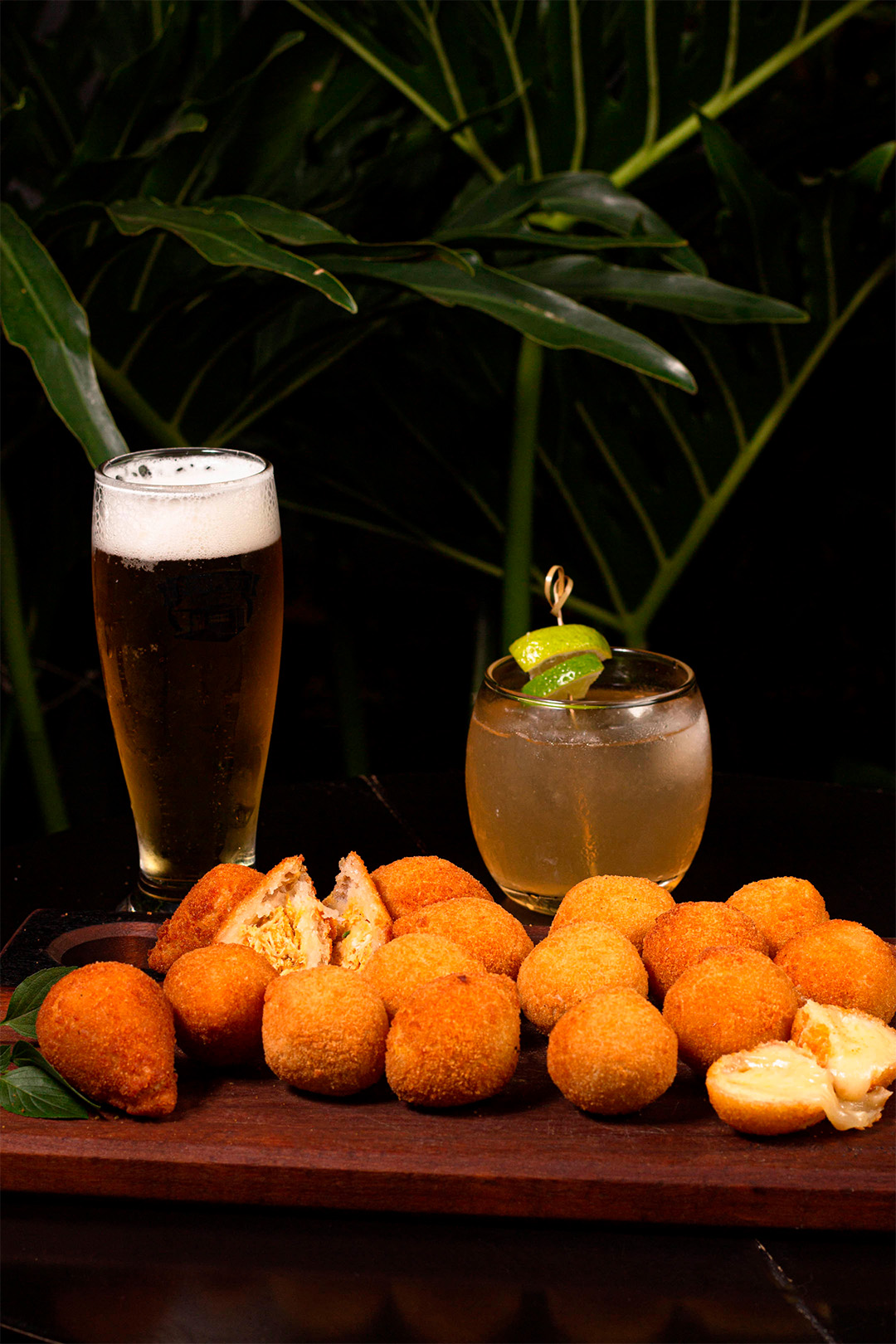 Tábua com mini coxinhas, atras copo com cerveja e copo com drink