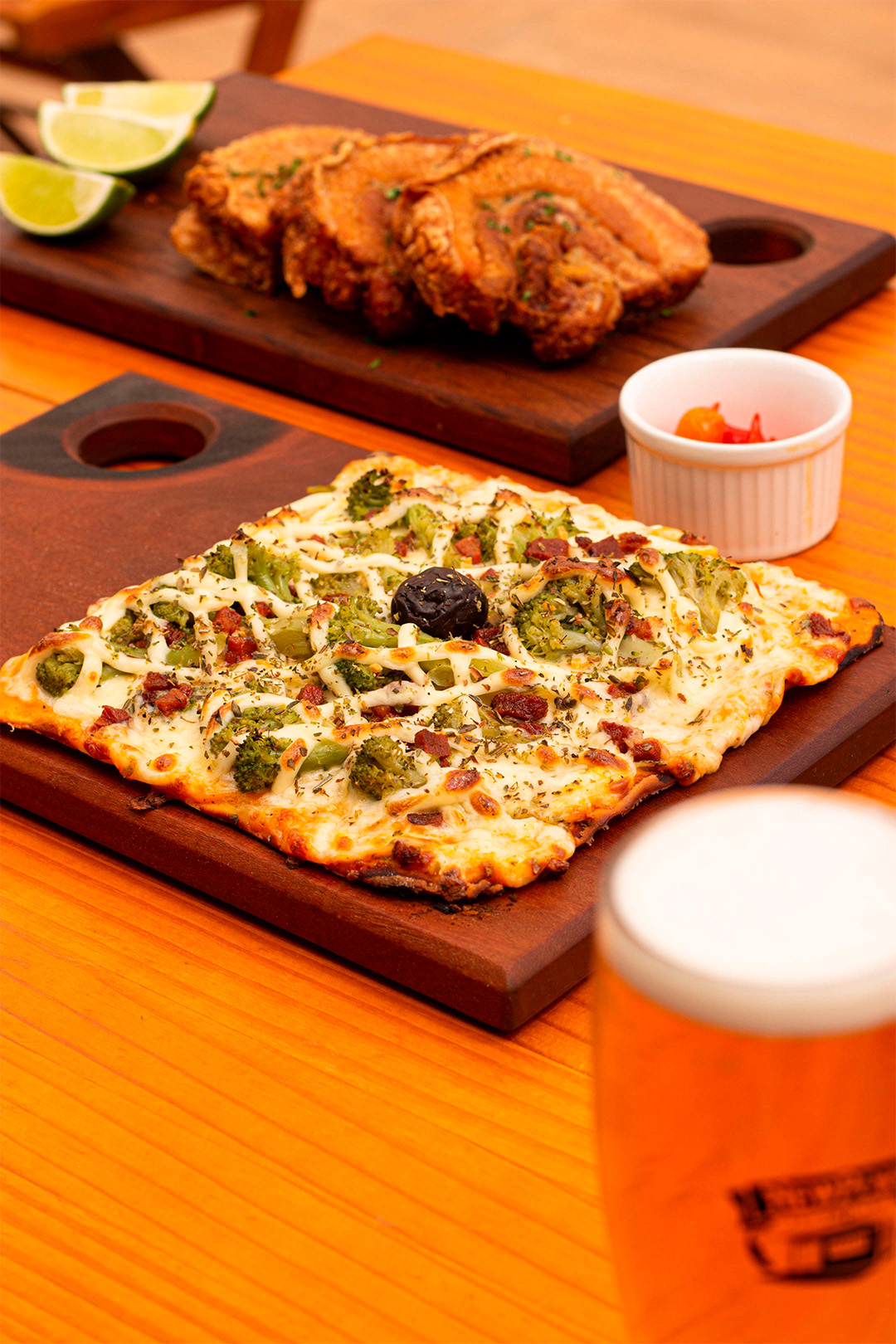 Tábua com pizza e ao fundo tabua com torresmo e limão