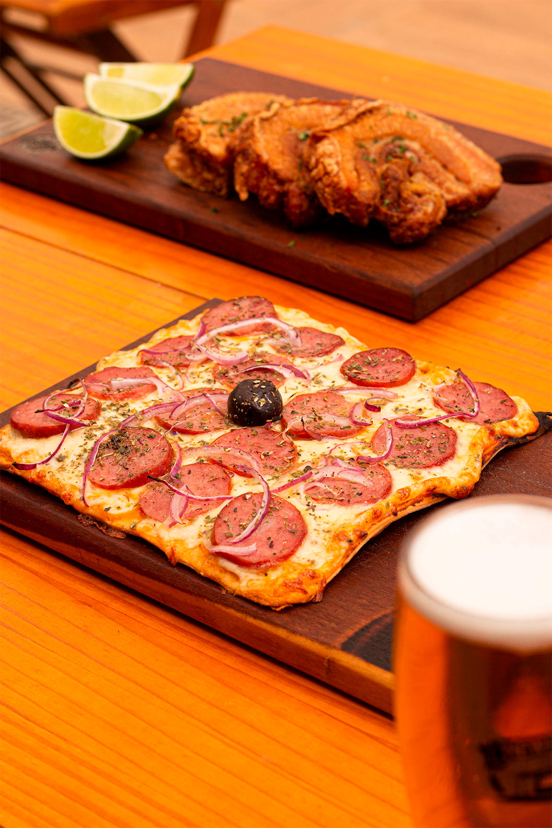 Tábua com pizza e ao fundo Tábua com torresmo e limão.